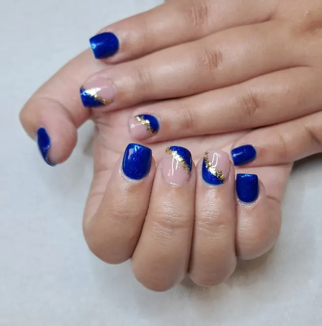 Pose de capsules bleues, deux ongles nude barrés d'or