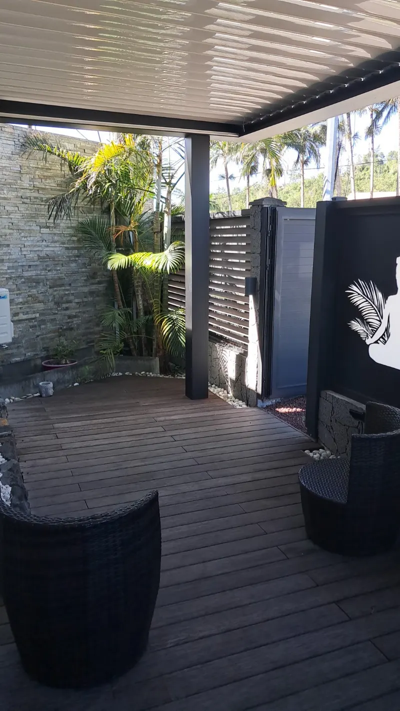 La terrasse de l'institut sous la pergola, les palmiers et le logo peint sur le panneau noir